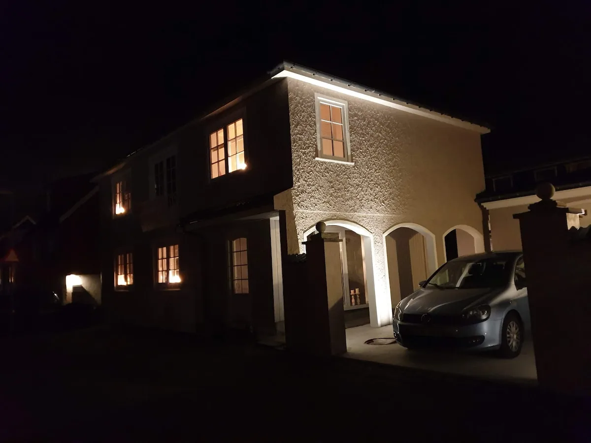 Façade de visitHOMES éclairée de nuit, hébergement à Leirvík